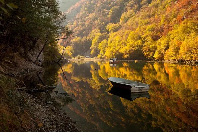 Boat reflected in a still forest lake in autumn
